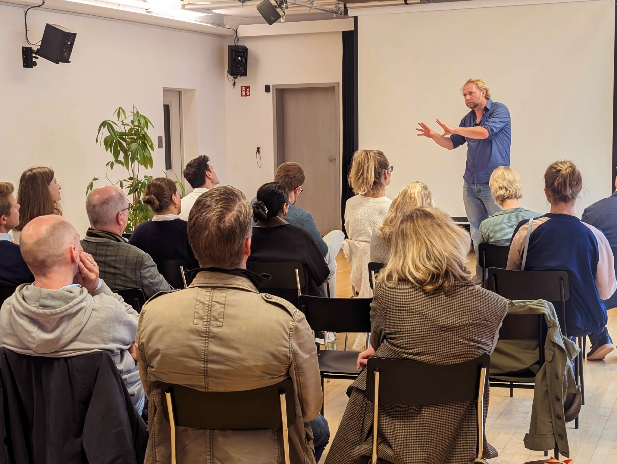 Nils rottgardt von Un-Label präsentiert vor einer Gruppe an Menschen im Un-Label Studio und gestikuliert mit den Händen.